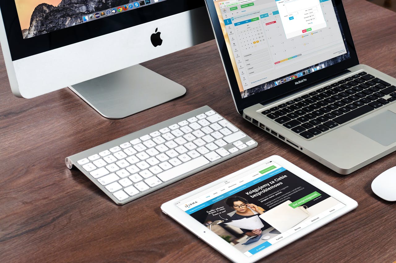 hero-homepage A sleek office desk setup featuring Apple devices: iMac, MacBook, and iPad.